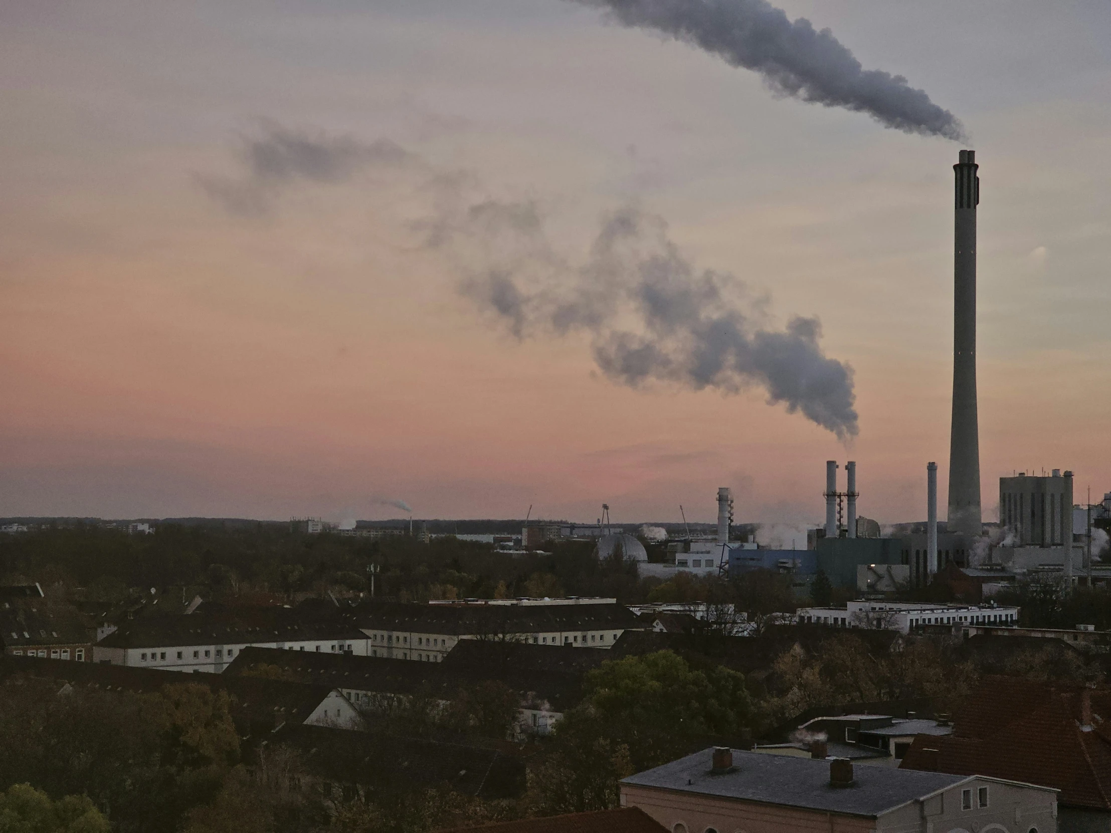 smoke billows from pipes in a city skyline