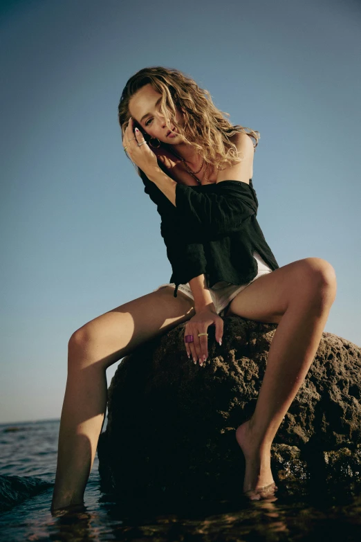 a woman sitting on the rocks is talking on her phone