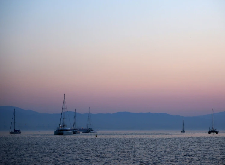 sail boats on open water with mountains in the distance