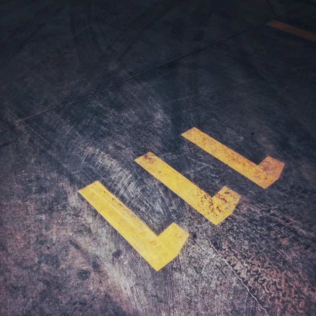 three yellow painted numbers are sitting on an asphalt surface