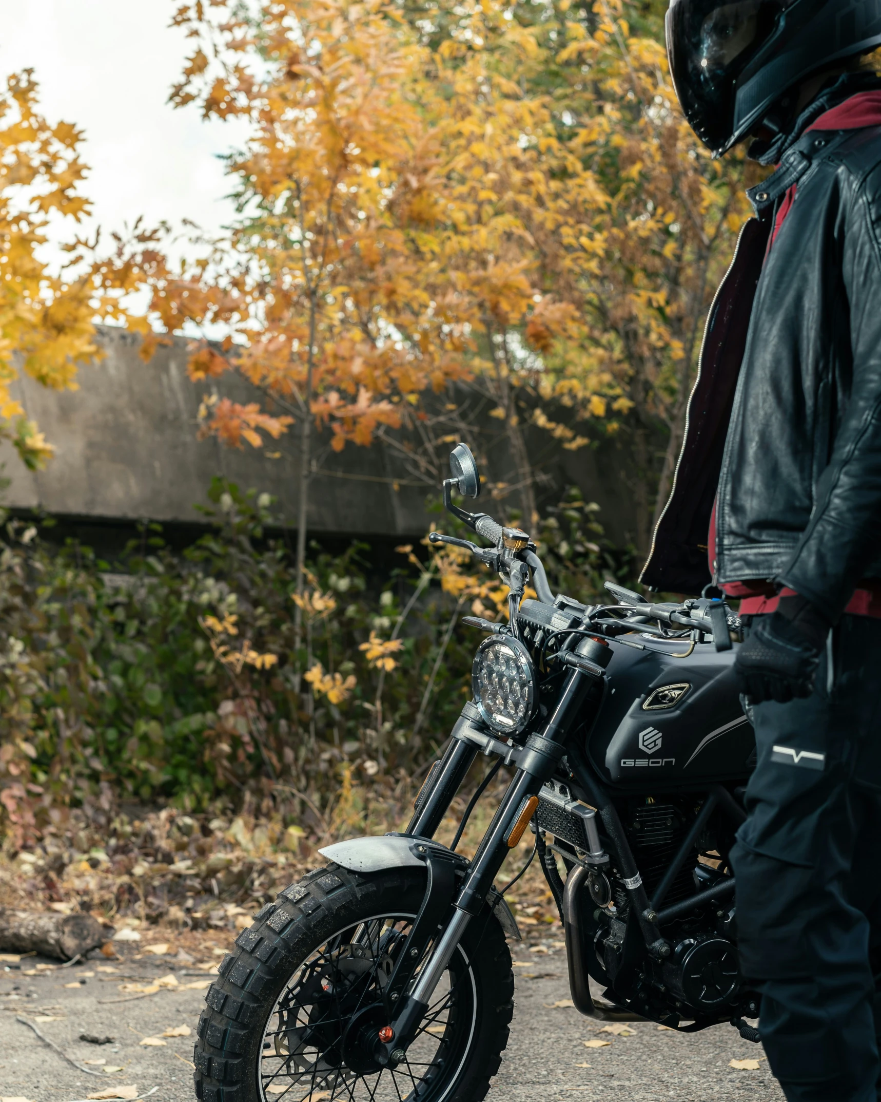 a person in full leather gear and with a helmet on stands next to a motorcycle