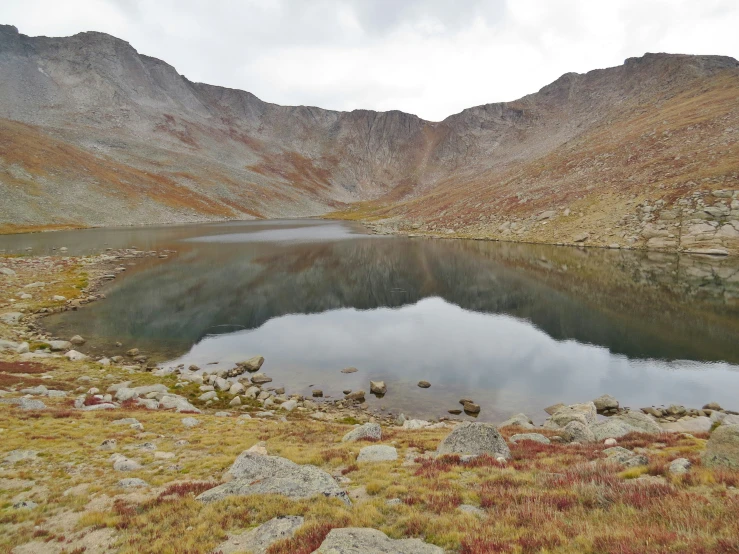 water surrounded by mountains and grass next to it