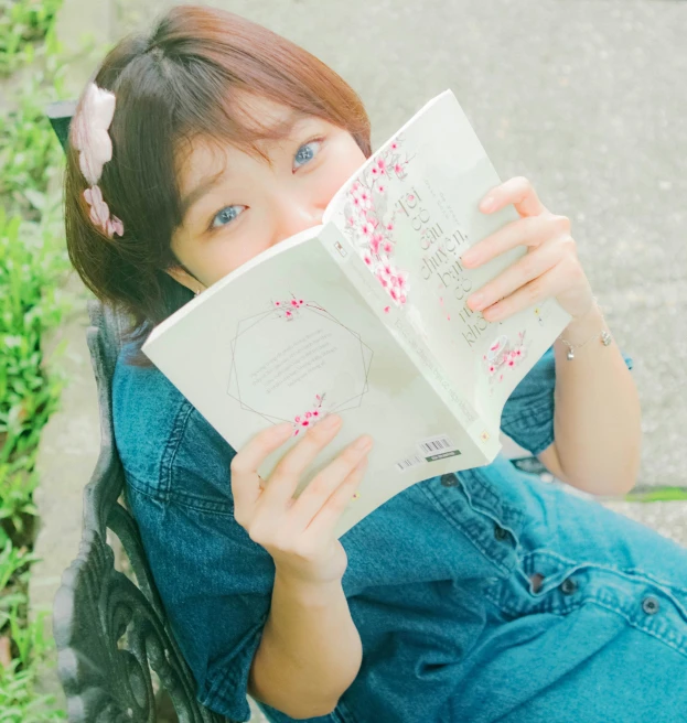 girl with red hair reading a book on a bench