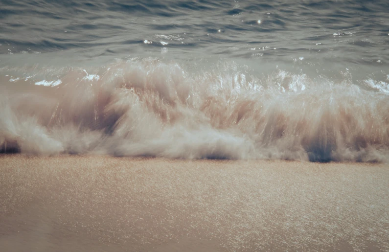 a wave crashes over a sandy shore