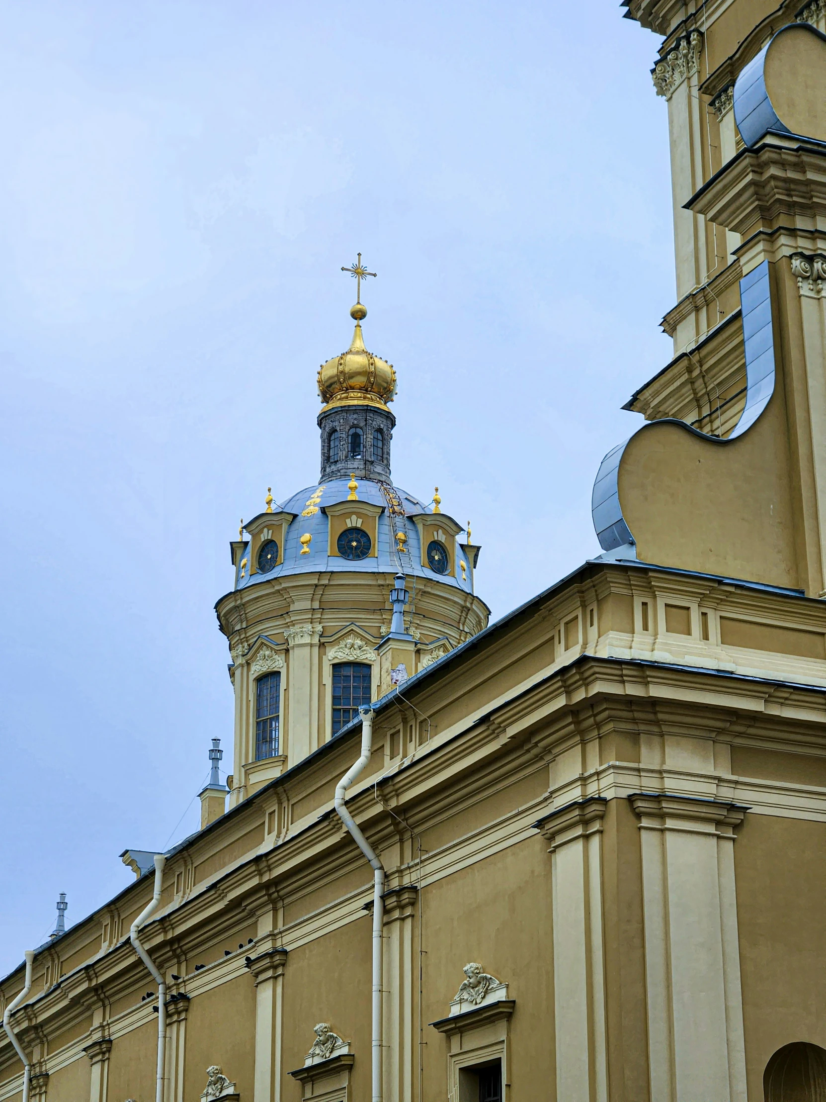a church has an ornate tower and is tan with a gold spire