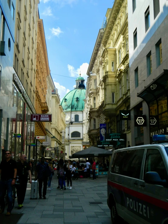 a street full of people and buildings with a clock tower in the background