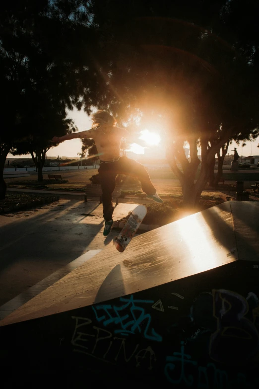 skateboarders ride their boards down a slope at sunset