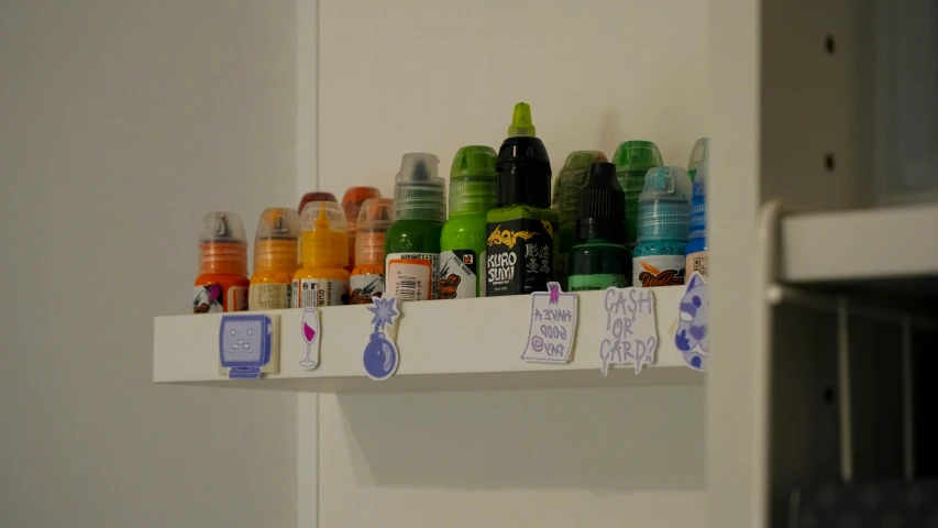 this shelf is filled with multiple bottles of craft supplies