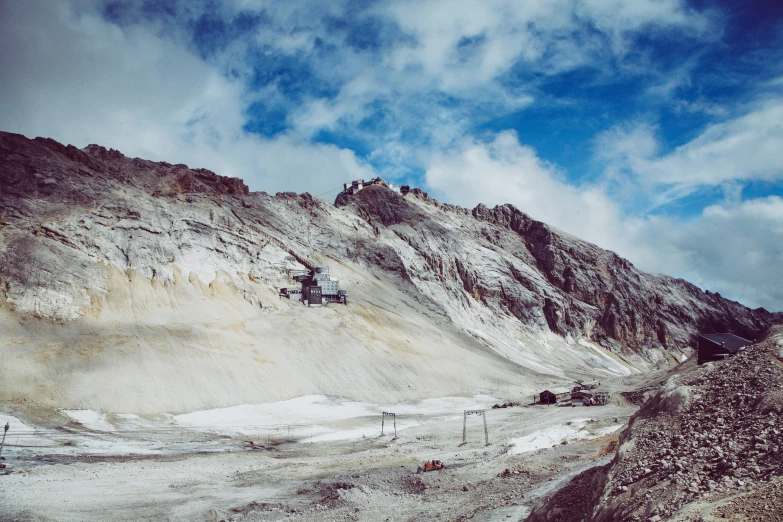 a dirt hill covered with snow under a cloudy sky