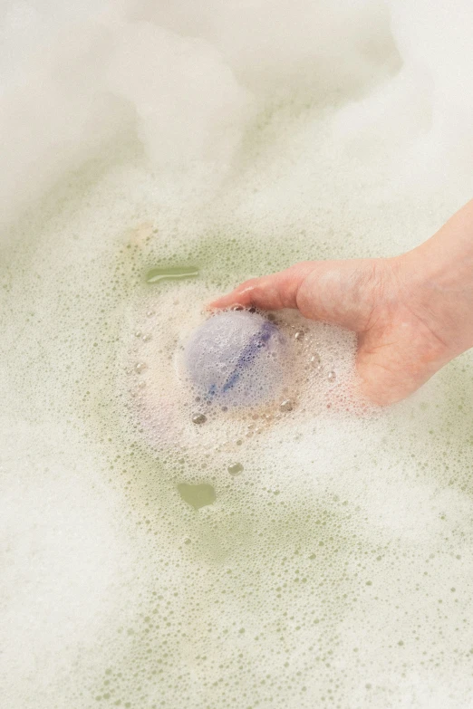 a hand is washing a blue flower in a large, round basin