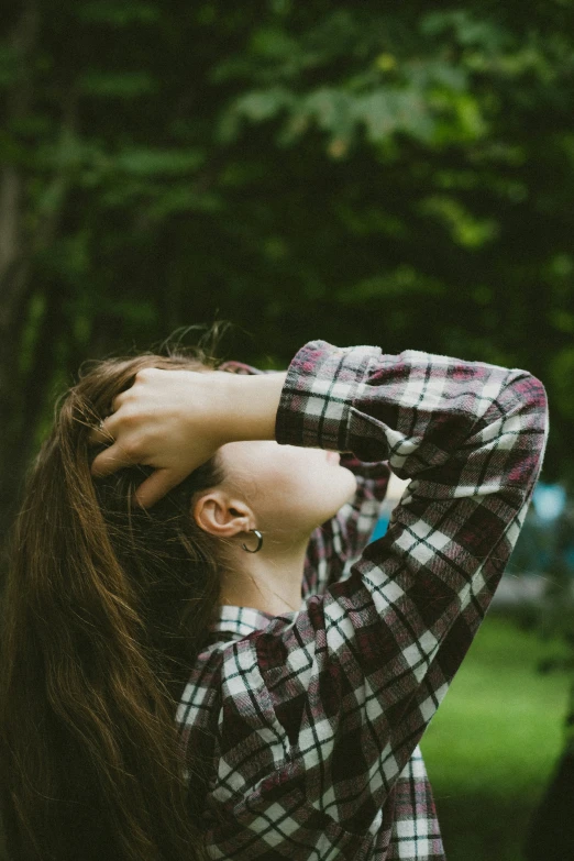 a girl standing in front of a tree with her eyes closed