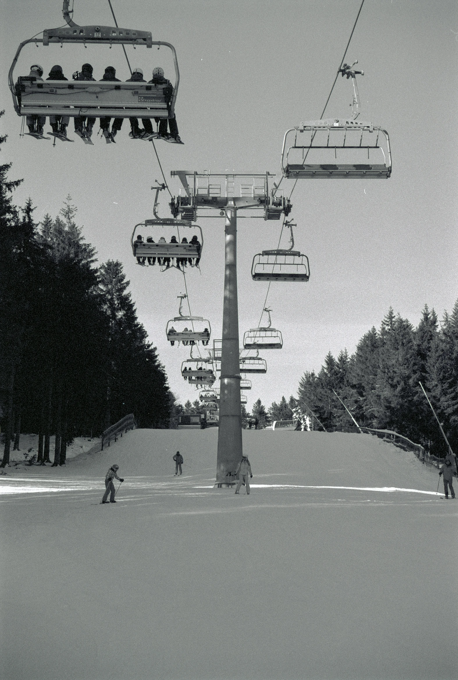 a couple of skiiers ride on the back of a lift