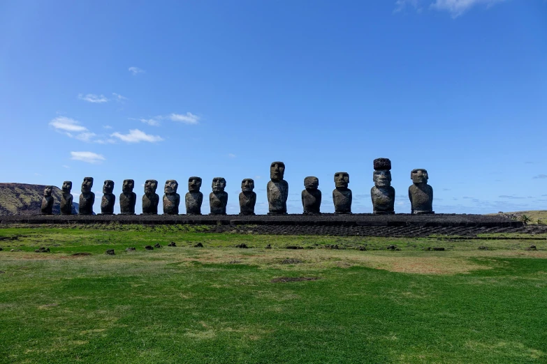 a row of sculptures sits on the side of a cliff