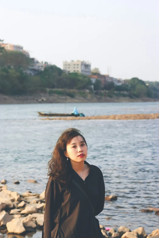 a woman standing next to a lake with a boat