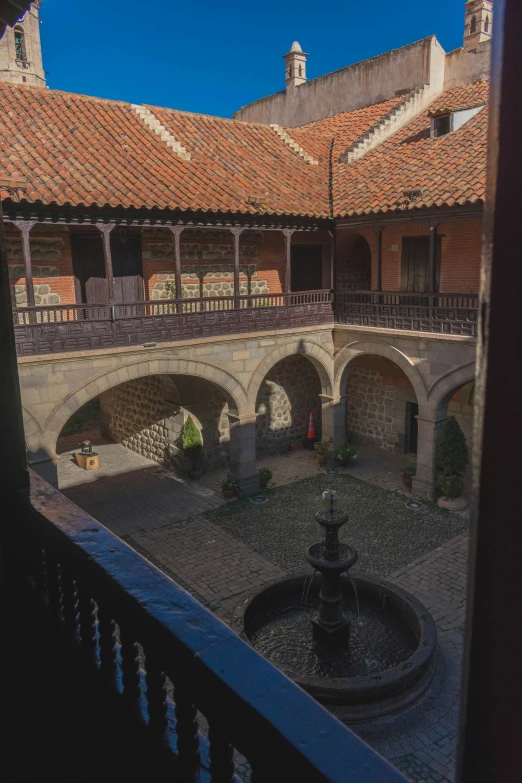 an outdoor courtyard features a fountain in the center and brick tiled roofs