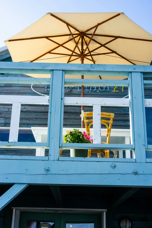 a house with patio furniture, patio umbrellas and potted plants