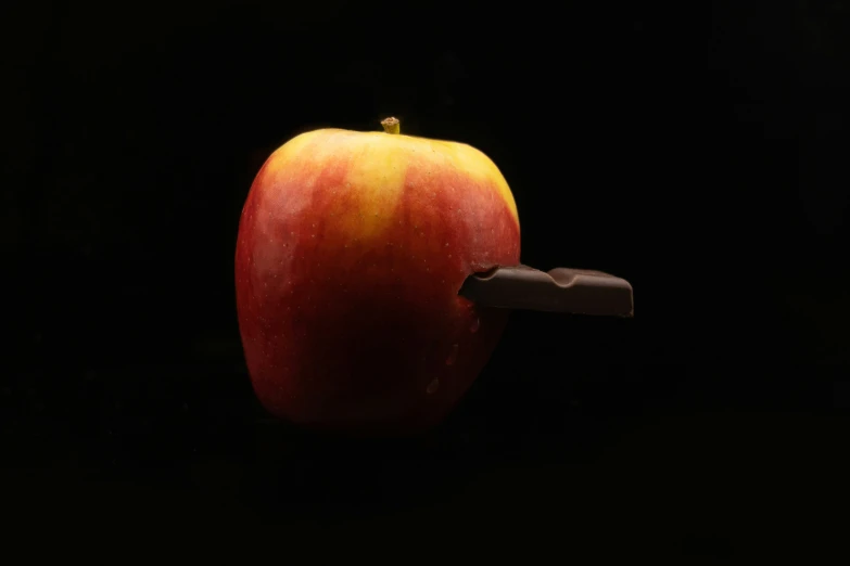 an apple and chocolate slice sitting together on a dark surface