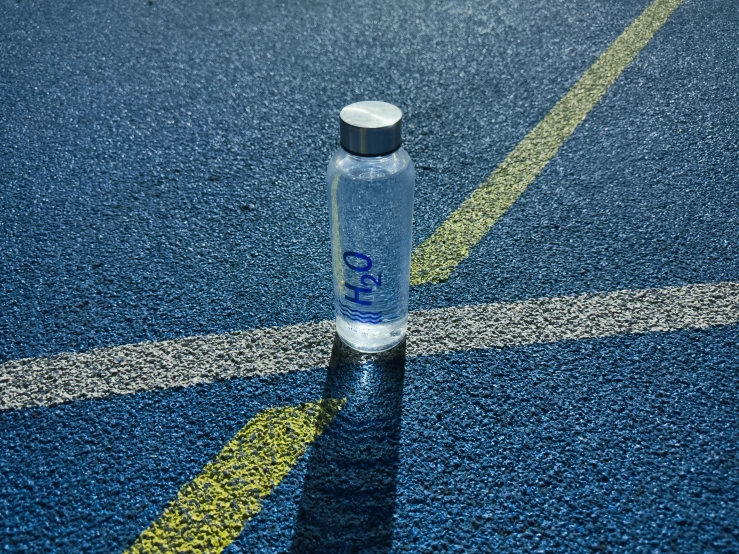 an empty bottle sitting on a tennis court