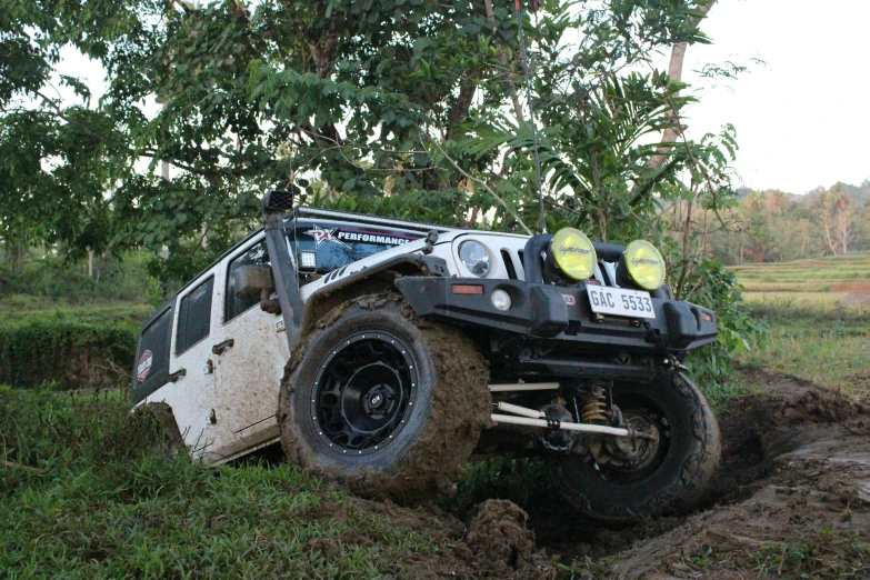 a white four wheel drive truck stuck in a mud dle