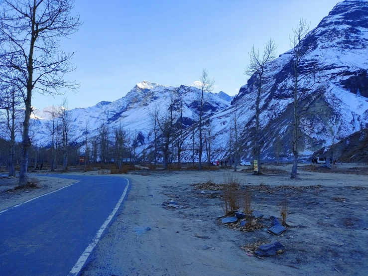 a paved road surrounded by snow covered mountains