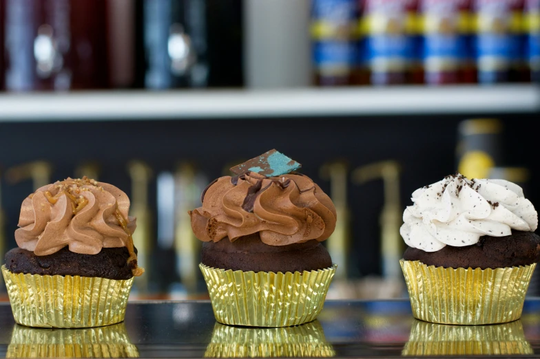 three different types of frosted cupcakes sitting on top of a metal table