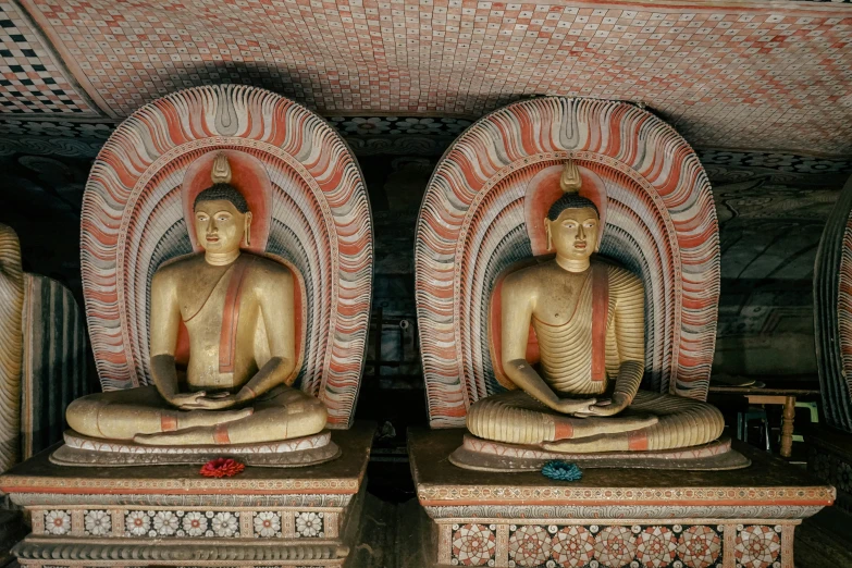 golden buddha statues sitting in a room with decorative wallpaper