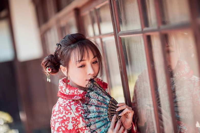 a young woman with a fan leaning against a building