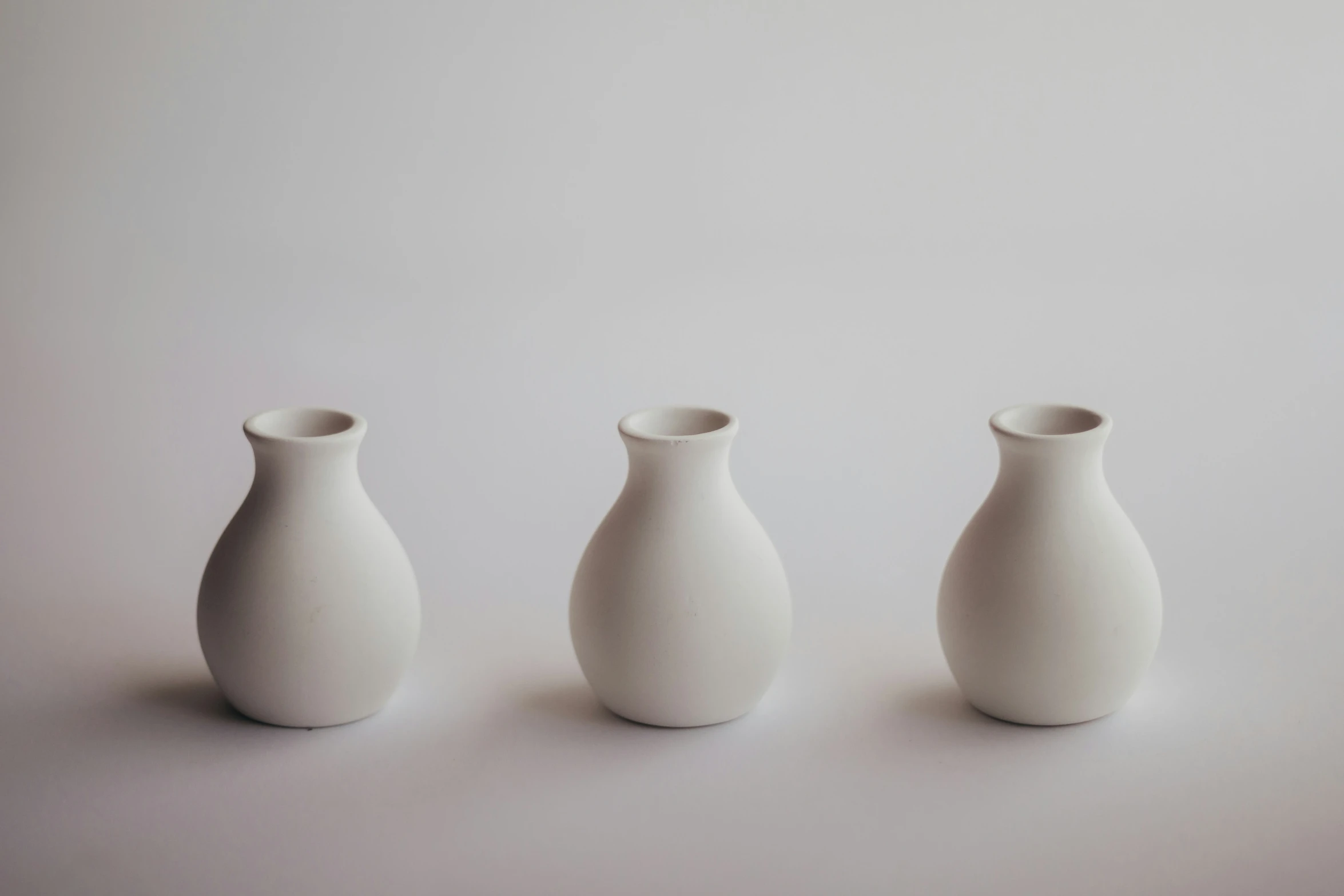 three different sized vases sit in a row
