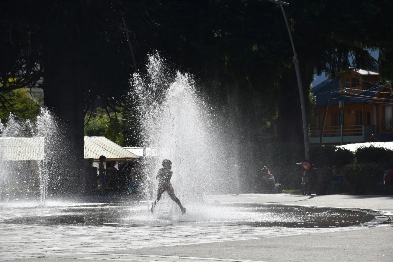 a woman plays in a fountain near trees