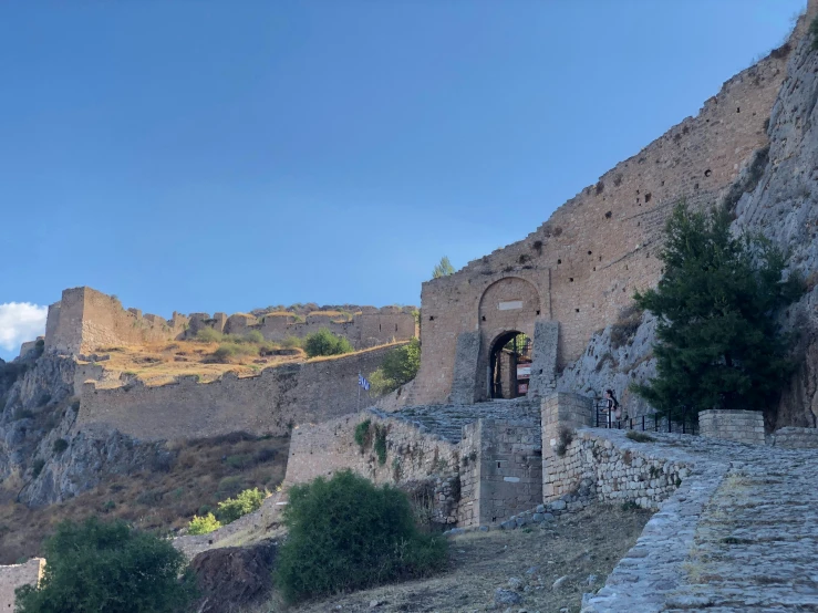 a rocky cliff side with a gate and some trees