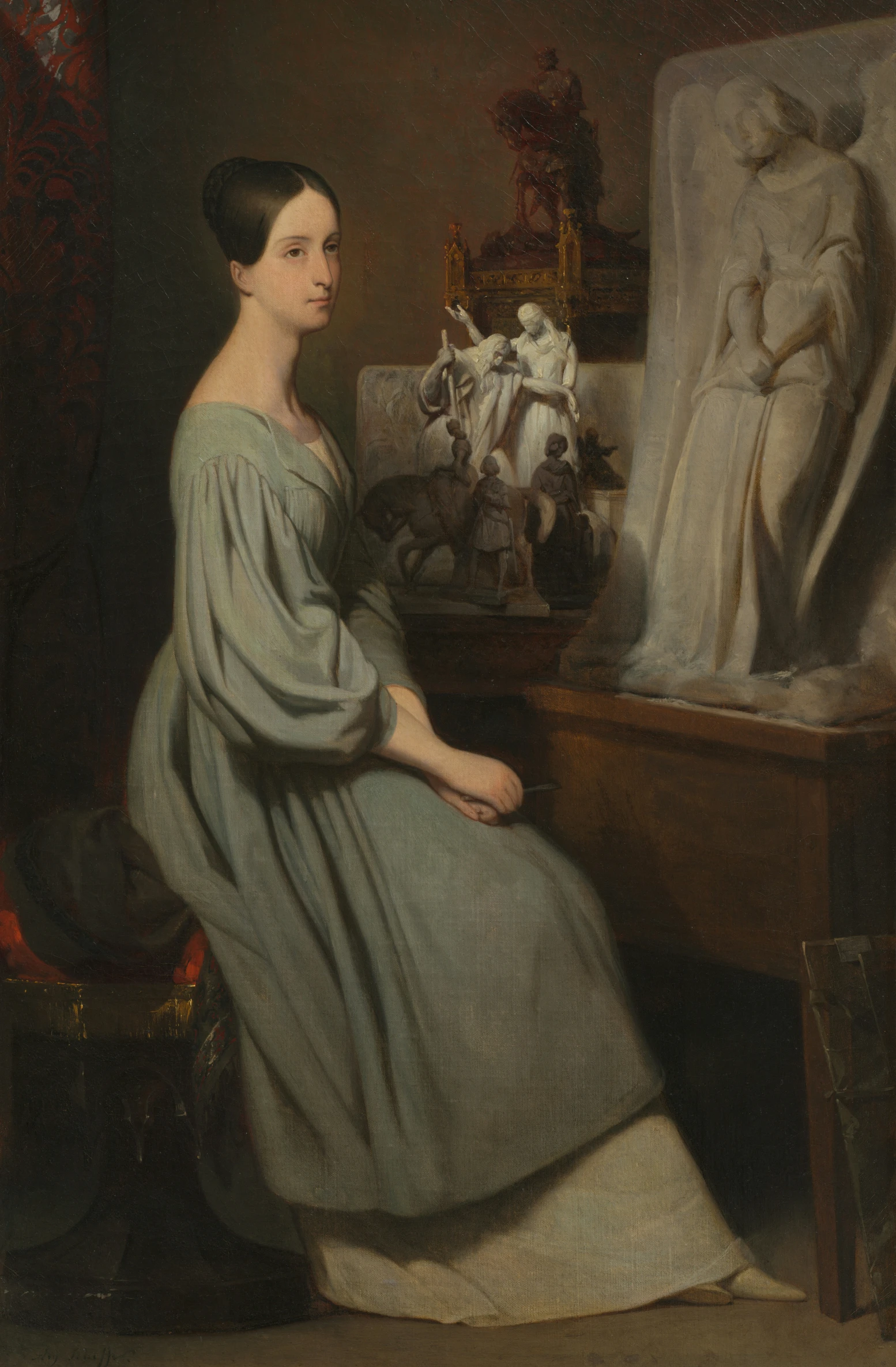the woman in the dress sits near an easel