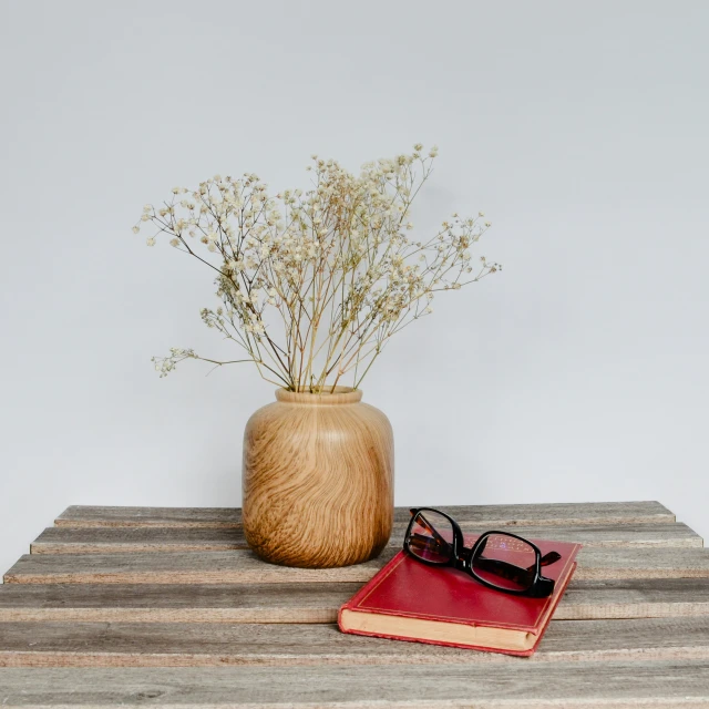 a book with glasses sits next to a flower pot