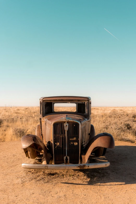 an old antique car sits in the middle of nowhere