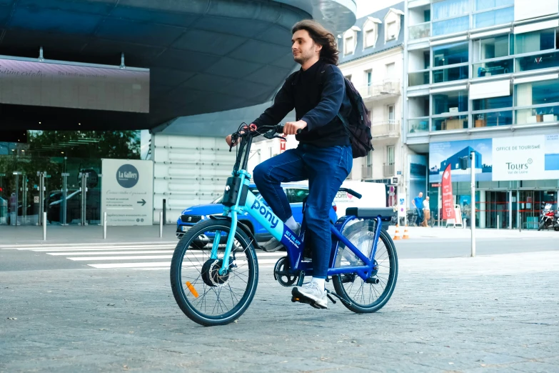 the man is riding a blue bike down the street