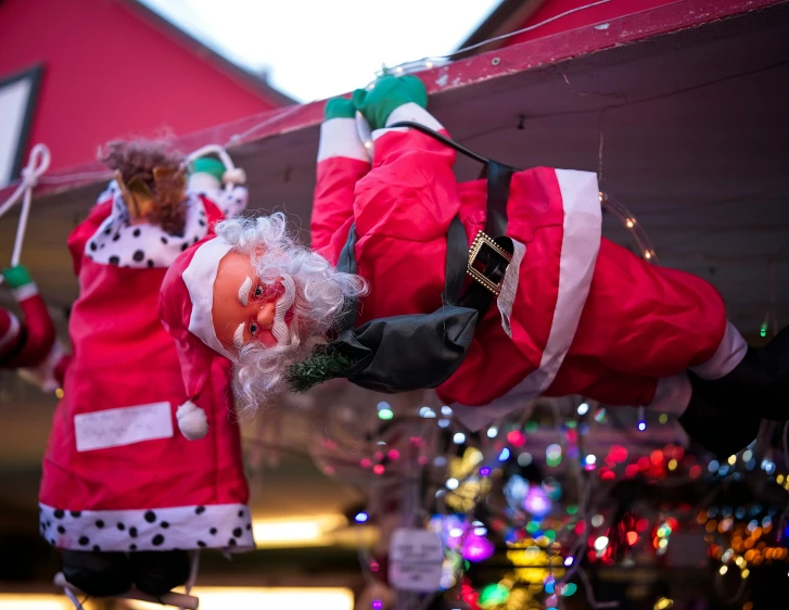 two dolls wearing red and white clothes holding up christmas decorations