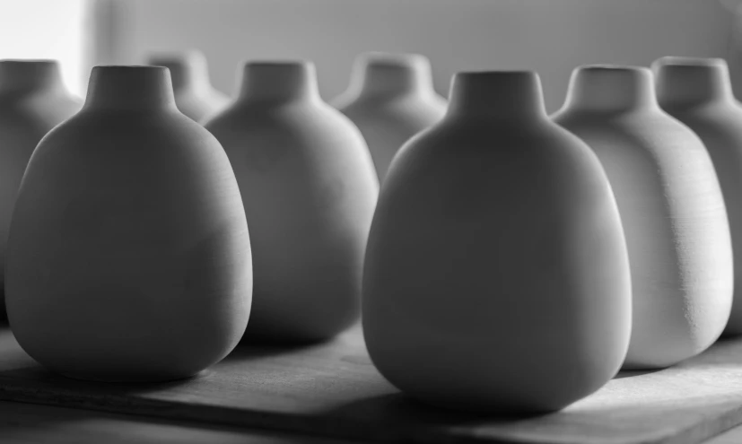 nine vases lined up on the surface and one is empty