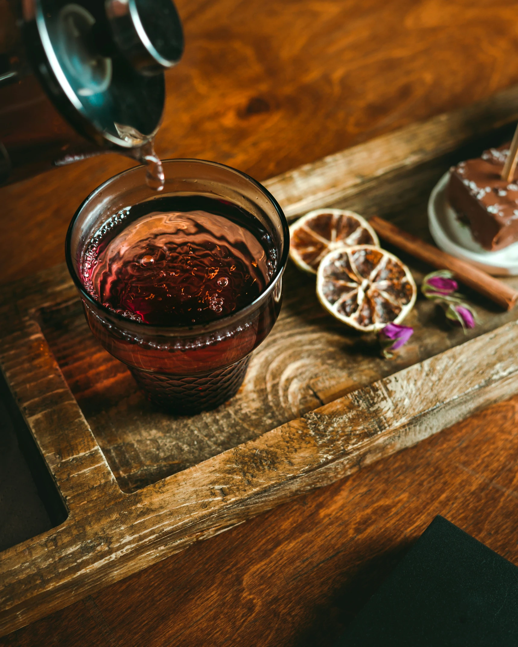 a brown table holding a glass with liquid in it