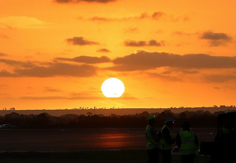 there are some men that are standing together at sunset