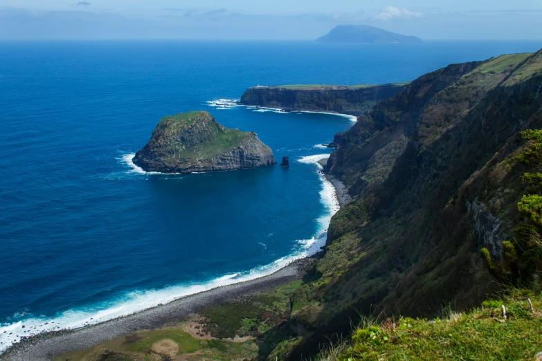 view from the mountain looking down at the ocean and a small island