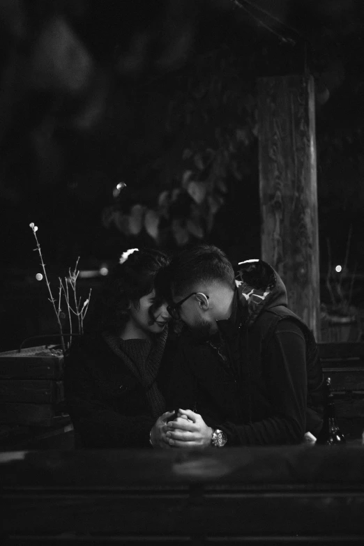 a couple cuddling under a tree and kissing in the dark