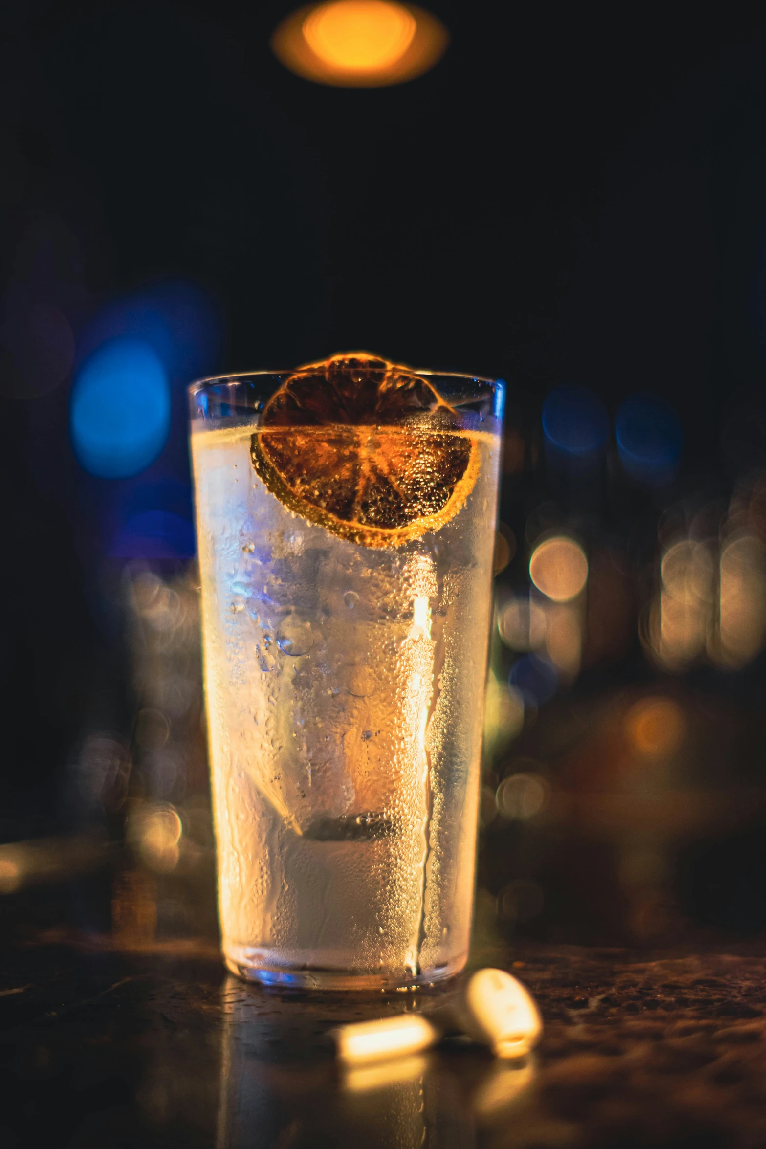 an orange wedge is on top of a clear glass