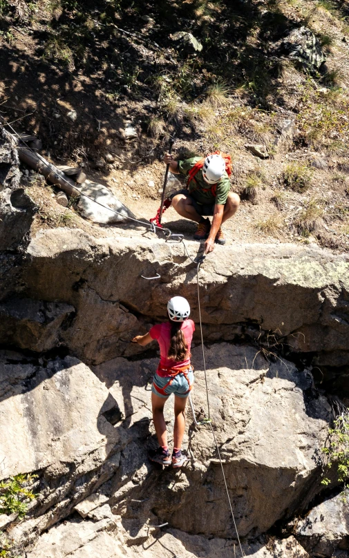 two climbers on rocks overlooking the ground and climbing