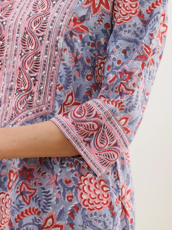 a woman wearing a blue red paisley top with a red and white stripe around the sleeves