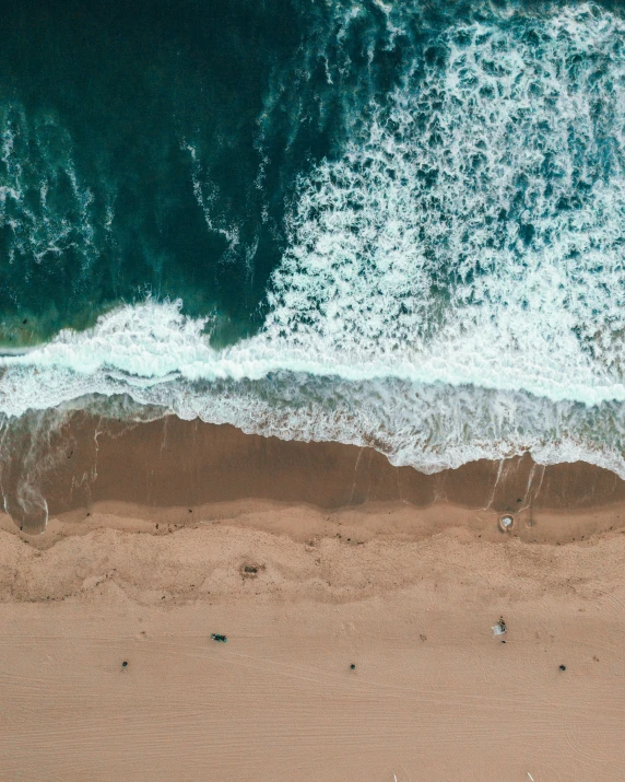 an aerial view of an ocean beach with waves and footprints