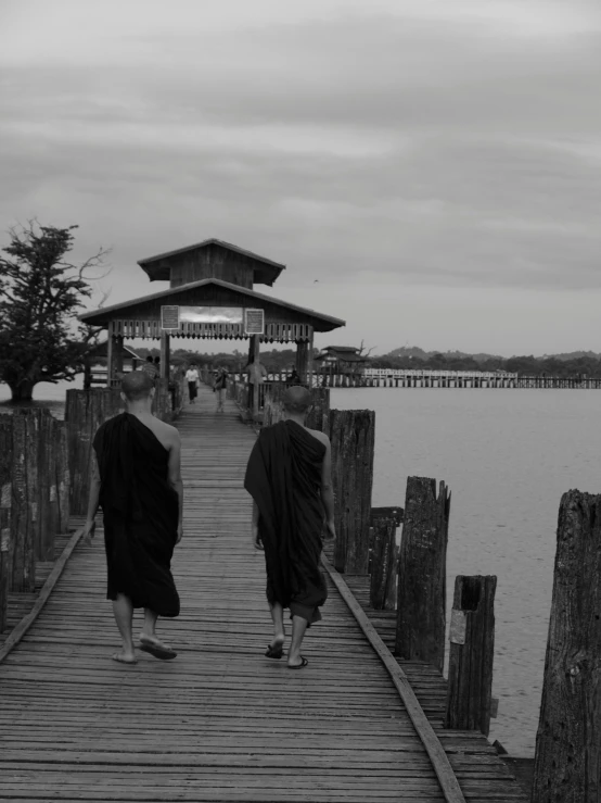 two monks walking along a dock to get off the water