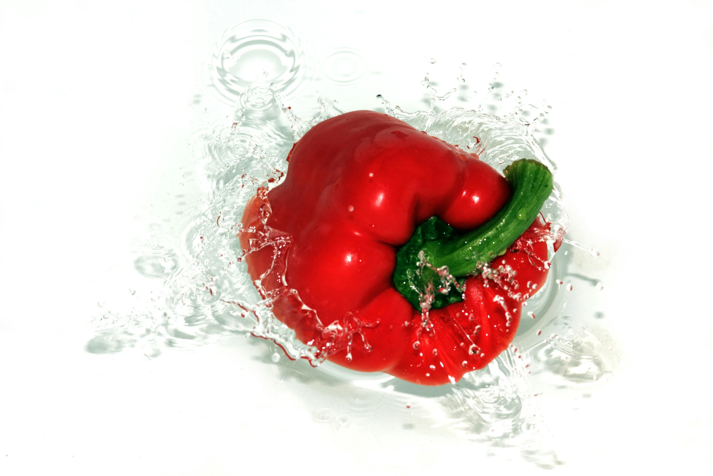 a red bell pepper splashing into water