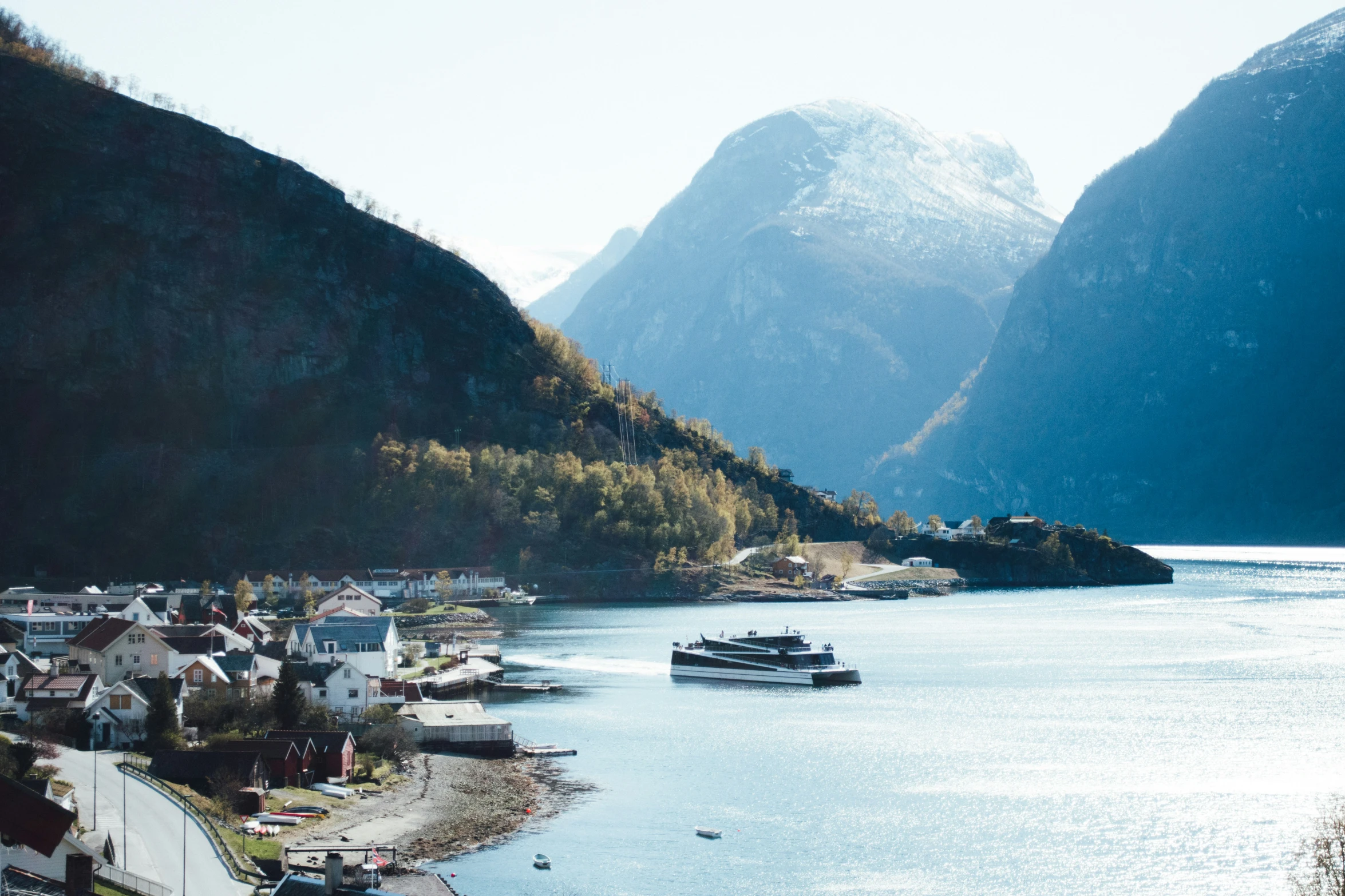 boat in water with mountains and houses by the shore