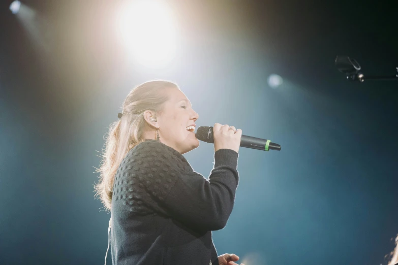 a woman sings on stage while looking down