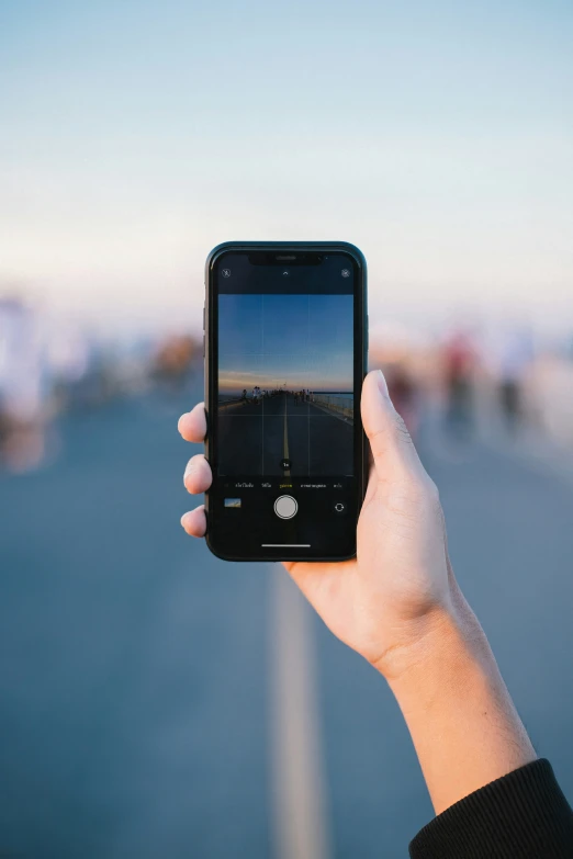 a person holding a cellphone taking pictures of a road