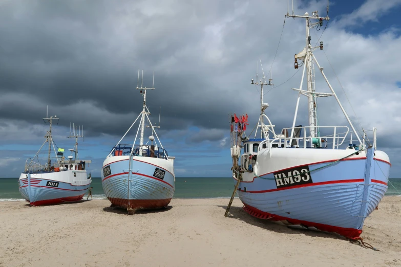 three boats sit on the sand and one is anchored